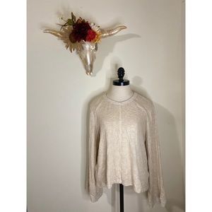 Cream colored soft sweater with wide sleeves.